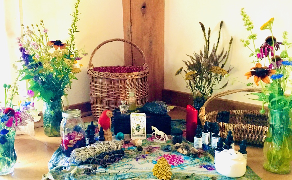A photograph of many bouquets of colorful flowers, tinctures, jars of medicines, bundles of herbs, candles, and figurines.